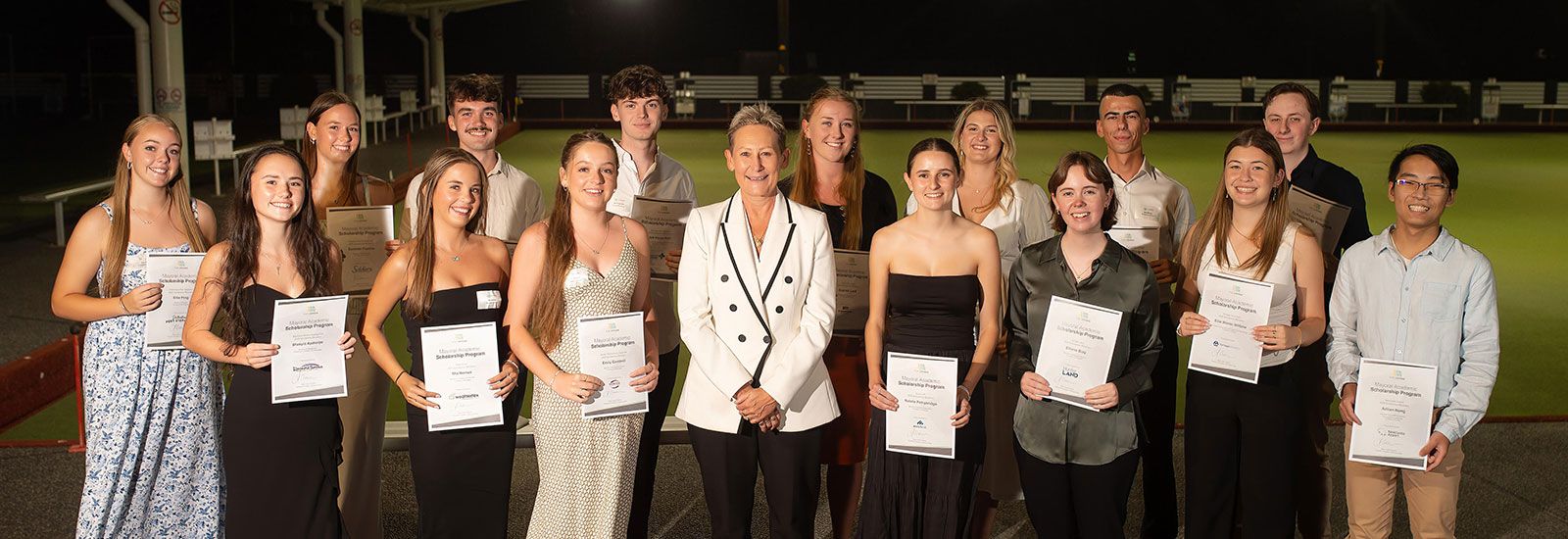 Young people holding certificates with the Mayor in the middle of the group, standing on a bowling green, smiling and happy banner image