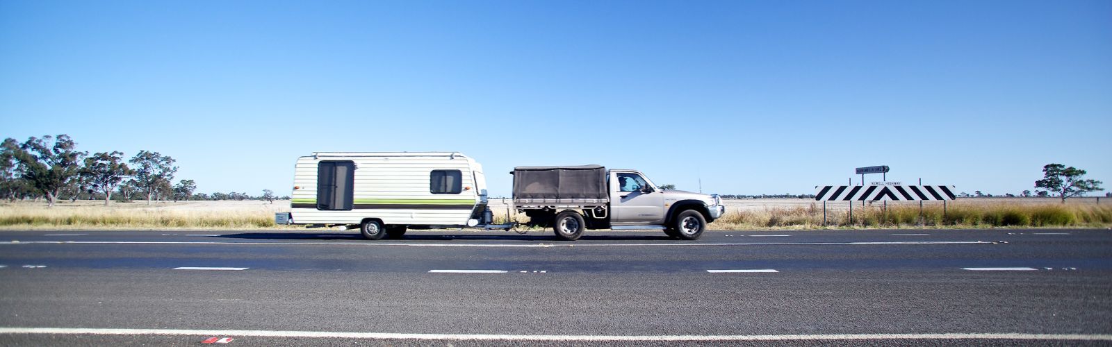 Ute towing caravan on road banner image